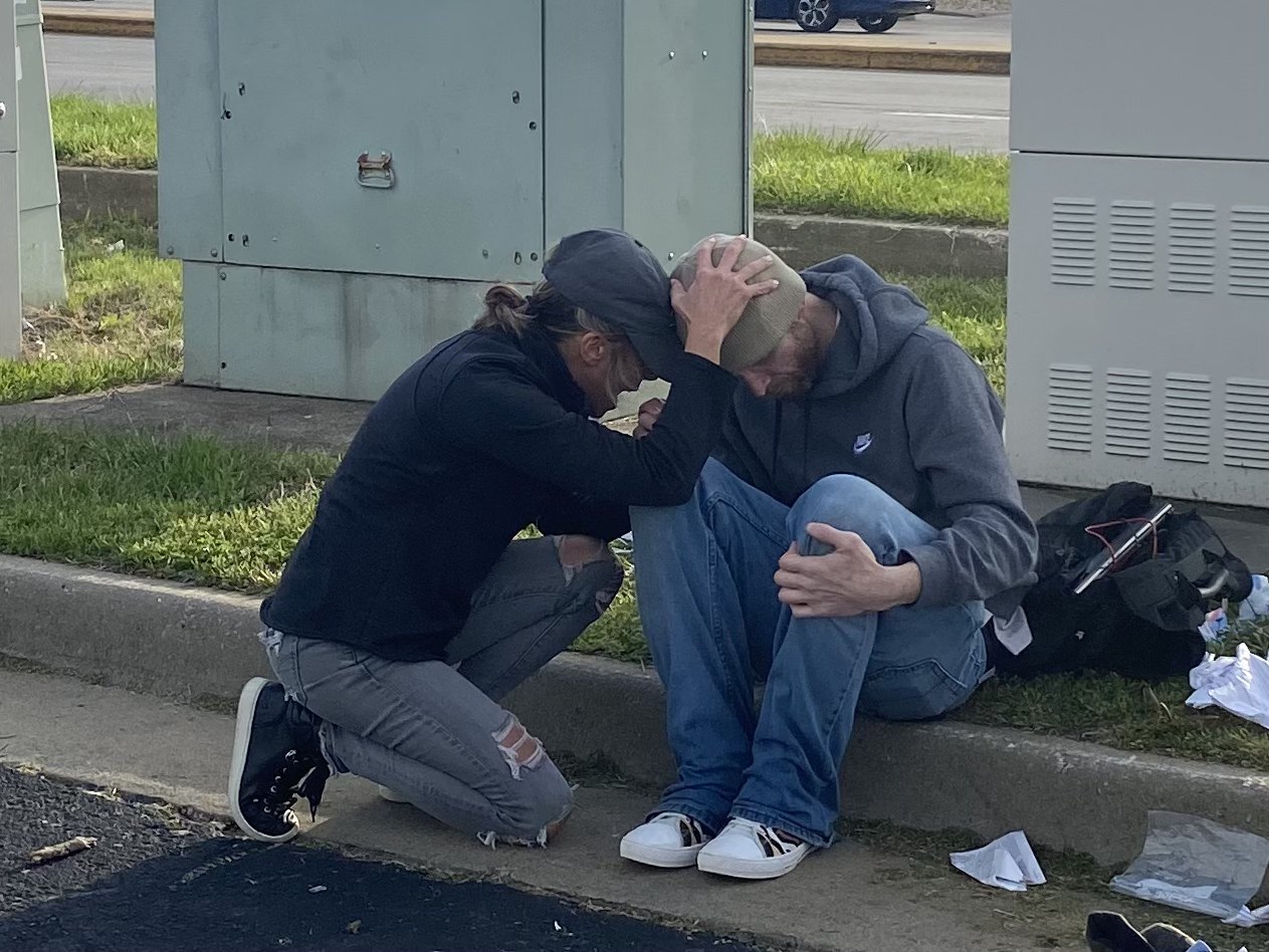 Praying with a man seated on a curb