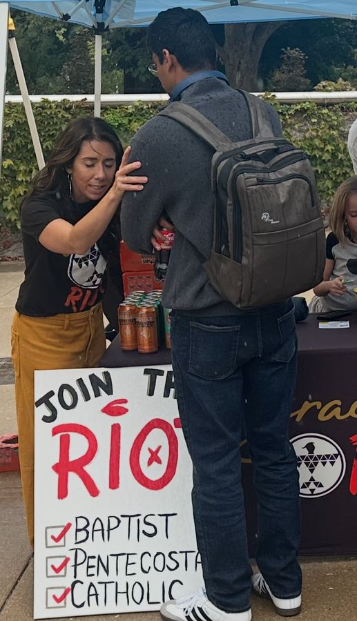 Praying with a man at the graceRIOT outreach table
